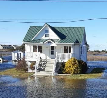 Elevated white home surrounded by water, which shows how home elevation is beneficial.
