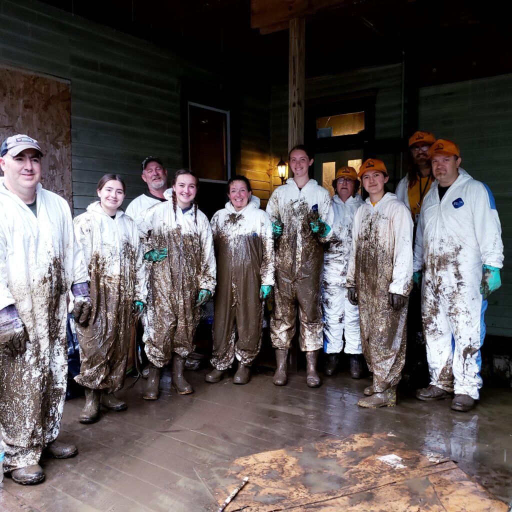 Team of people lined up for photo in muddy gear.